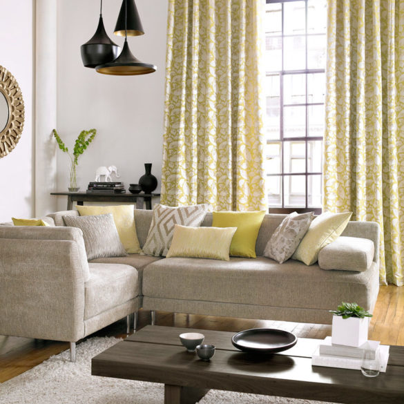 salon avec majorité couleur jaune. Table canapé avec fenêtre et rideaux motif